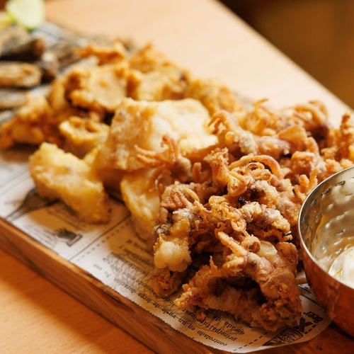 a tray of fried food with a bowl of mayonnaise on a table