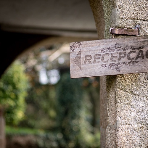 uma placa de madeira com a palavra recepcao ao lado de uma parede de pedra