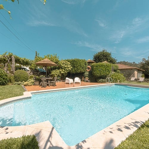 una gran piscina rodeada de césped y muebles en un día soleado