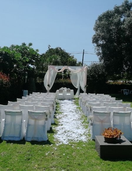 uma cerimônia de casamento com cadeiras brancas e um gazebo branco