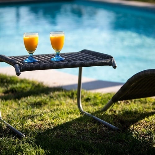 duas taças de suco de laranja em uma mesa ao lado de uma piscina