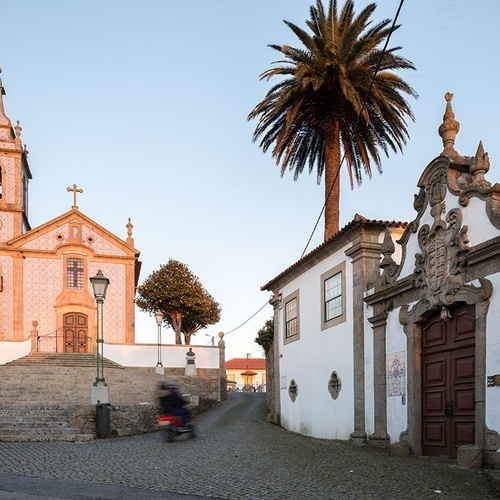 uma igreja com um relógio e uma palmeira ao fundo