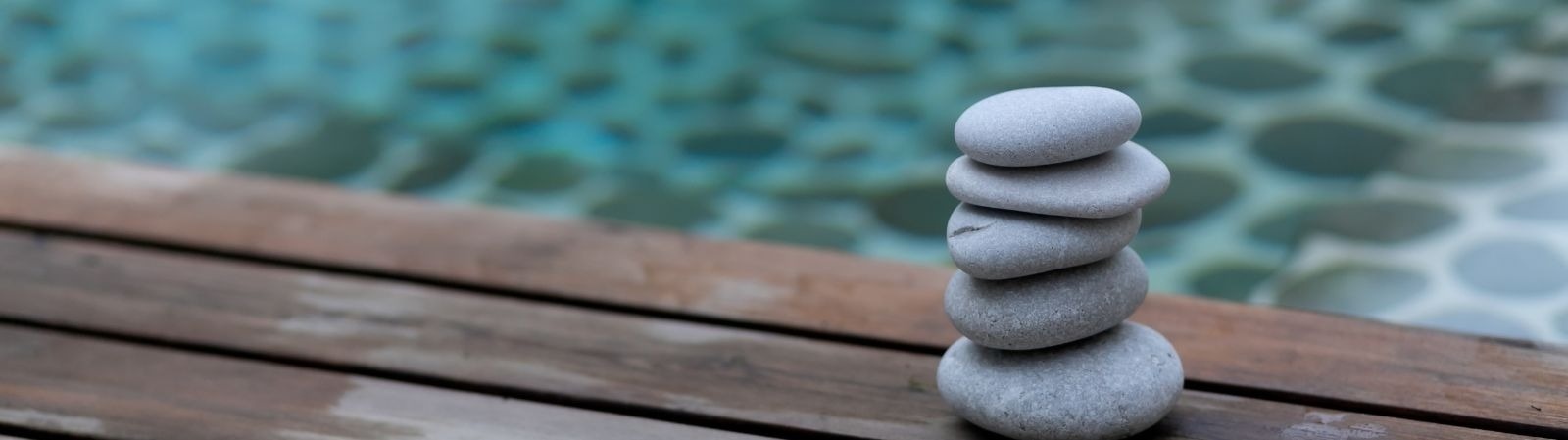 uma pilha de pedras está sobre uma mesa de madeira ao lado de uma piscina