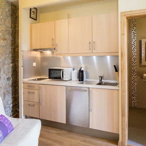 una pequeña cocina con gabinetes de madera y electrodomésticos de acero inoxidable