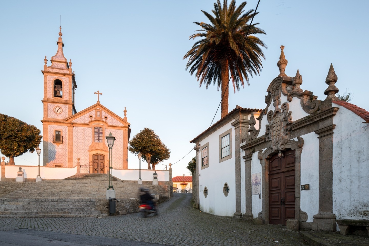 uma igreja com um relógio na torre e uma palmeira ao fundo