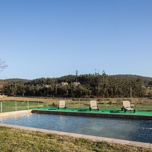 uma piscina com cadeiras ao redor e uma cerca de vidro