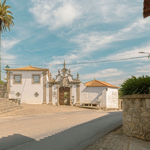 um prédio branco com uma porta de madeira e uma palmeira ao fundo