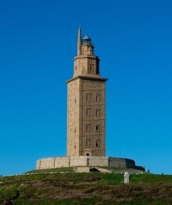 une grande tour de phare en pierre est assise au sommet d' une colline .