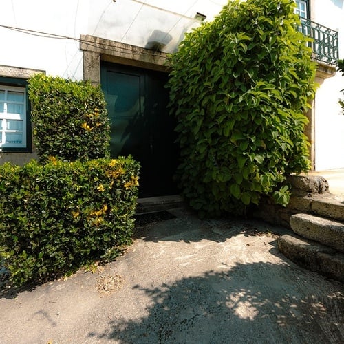 a porta da frente de uma casa está cercada por arbustos verdes