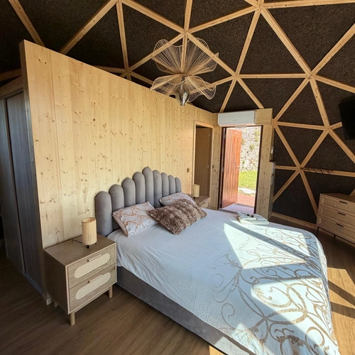 Cama confortável em quarto de hotel geodésico com decoração natural, ideal paraQuinta São Miguel de Arcos.