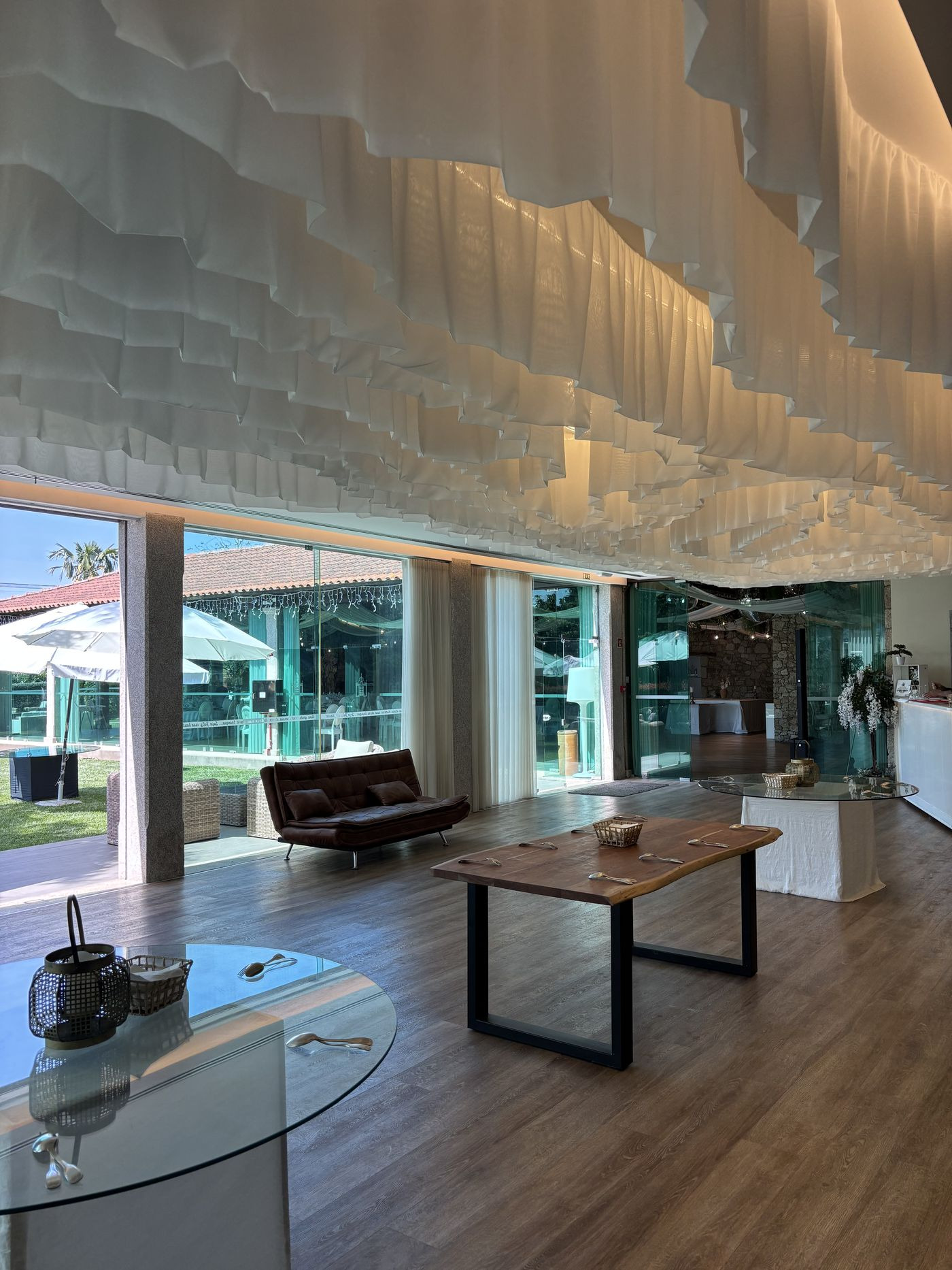 Sala de estar envidraçada com sofás e vista para o jardim.