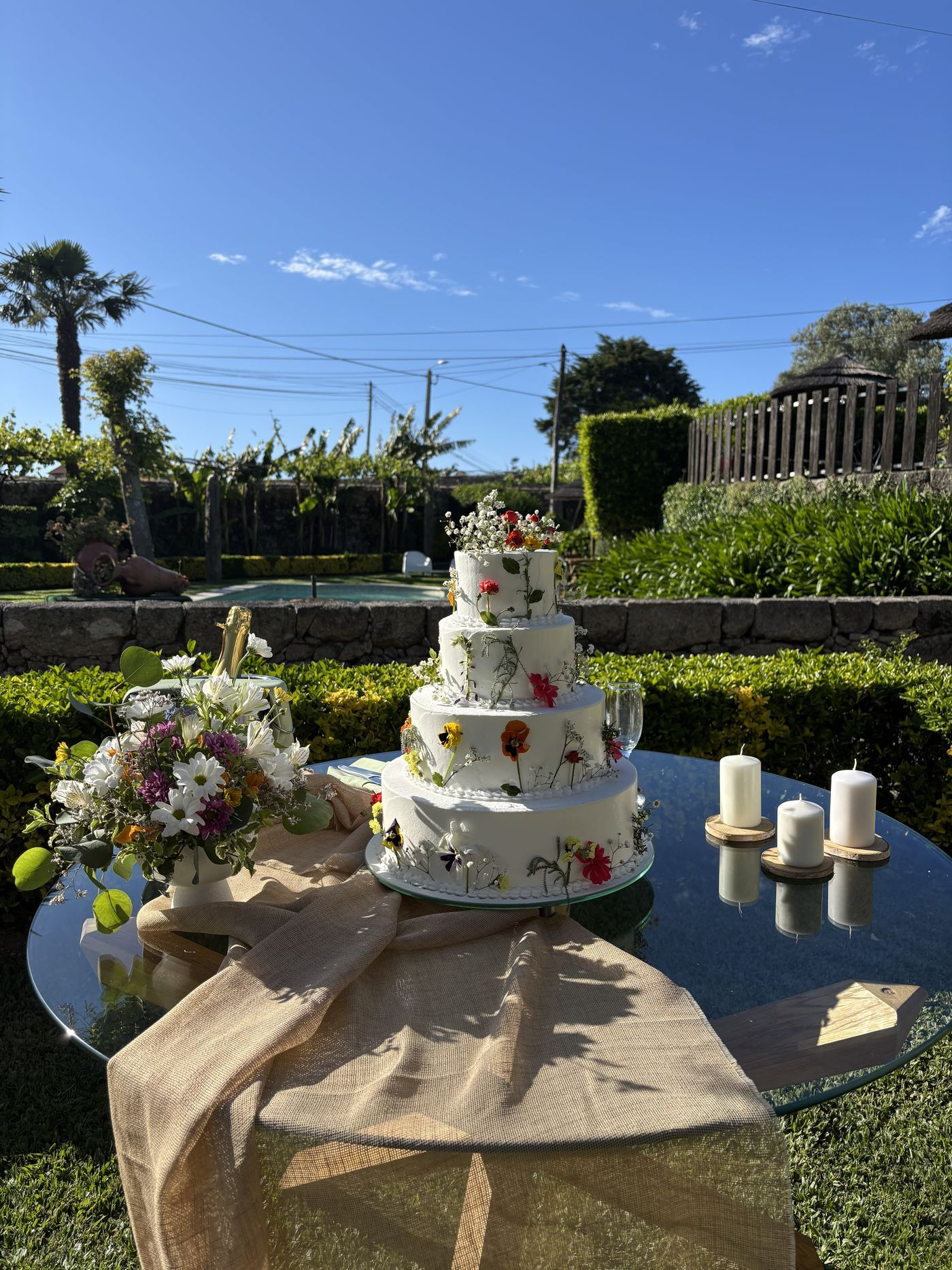 Bolo de casamento de vários andares no jardim, junto à piscina.