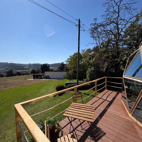 Deck com mesa e cadeiras com vista Quinta São Miguel de Arcos para paisagem rural ensolarada.