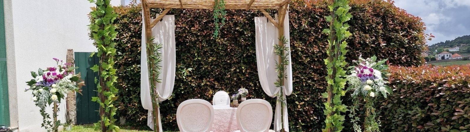 uma mesa e cadeiras estão em frente a um pérgola decorado com folhas e flores .