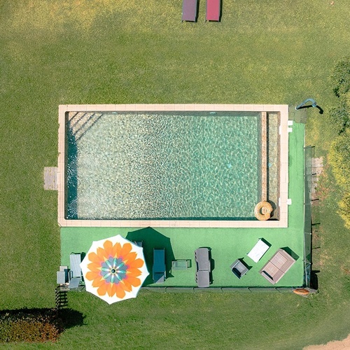 uma vista aérea de uma piscina com um guarda-chuva em cima