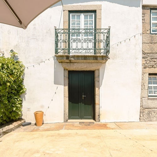 uma casa branca com uma porta verde e uma varanda