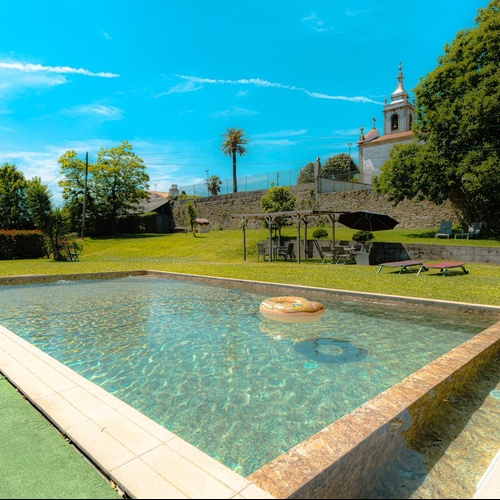 una piscina rodeada de césped y sillas en un día soleado