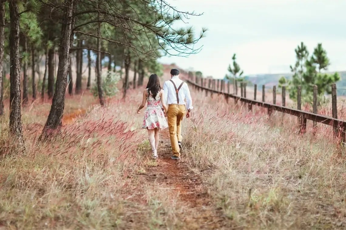 um homem e uma mulher estão andando por um caminho em um campo