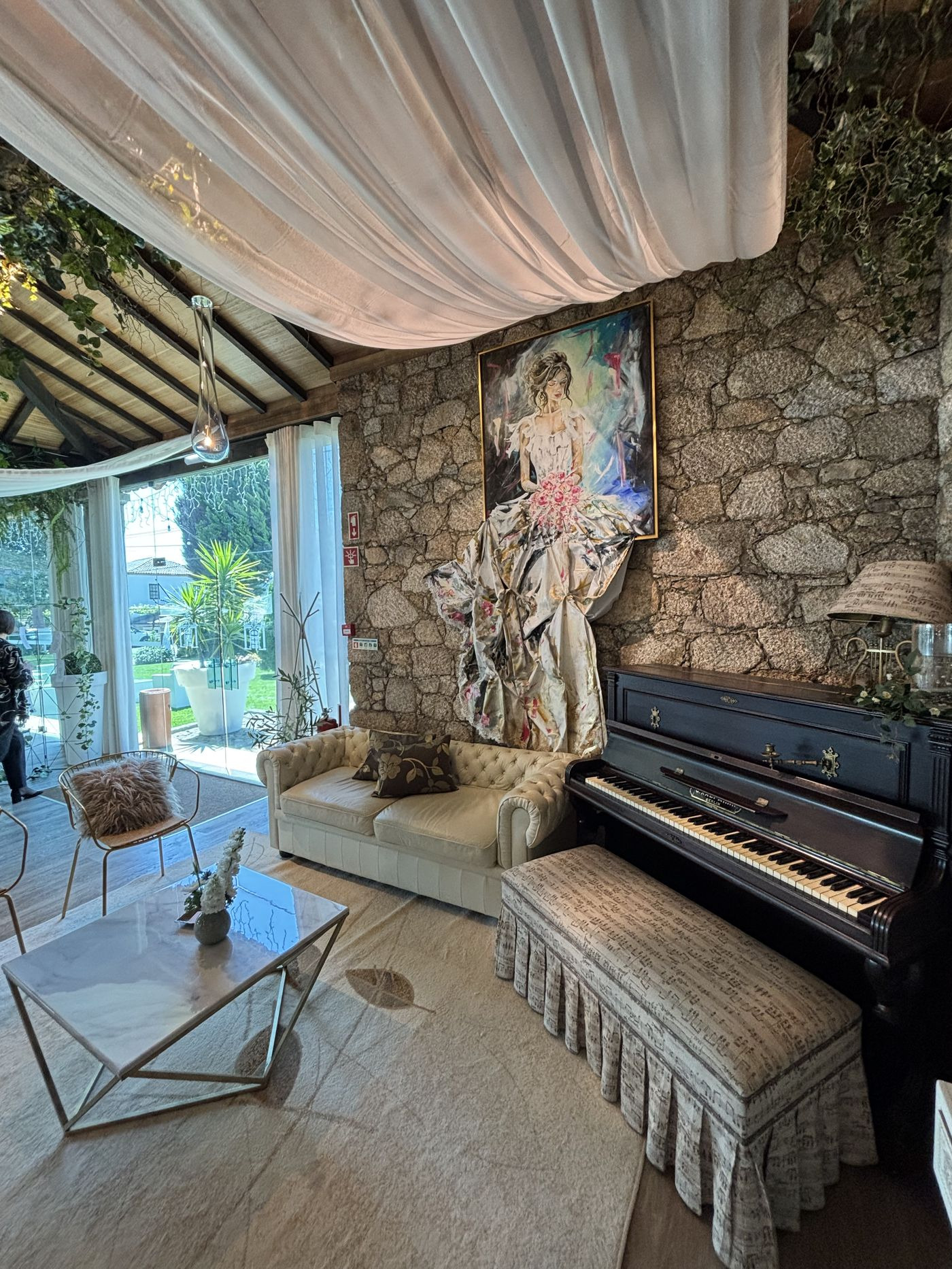 Sala de estar com piano vertical e parede de pedra rústica do solar.