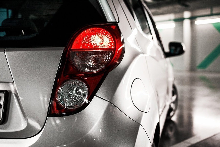 a silver car with a red tail light is parked in a parking garage