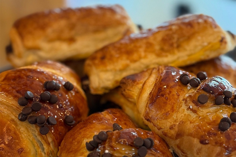a person laying on a bed with a book and a cup of coffee