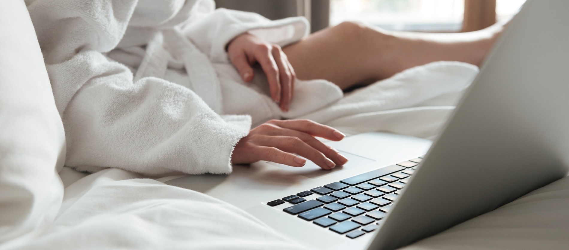 a person in a bathrobe is typing on a laptop