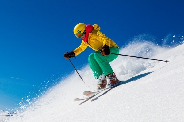 a person wearing a yellow jacket and green pants is skiing down a snowy hill