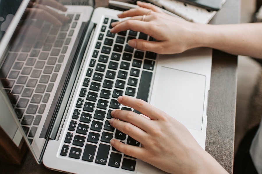 a person is typing on a laptop with the shift key visible