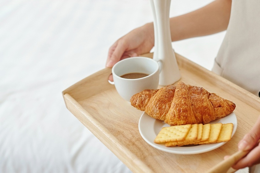 a person laying on a bed with a book and a cup of coffee