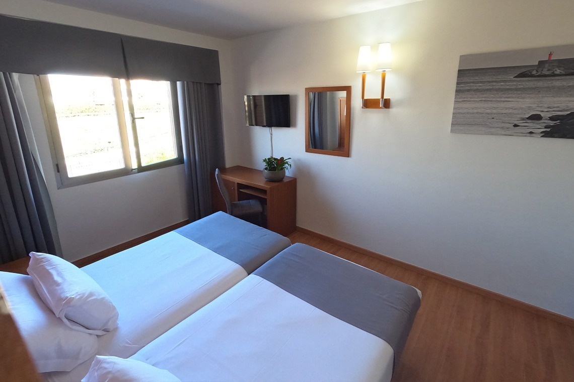 a hotel room with two beds a desk and a television