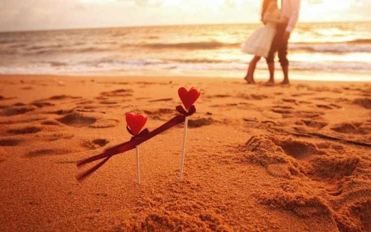 Coppia abbracciata sulla spiaggia al tramonto con cuori. Sea You: Port Saplaya
