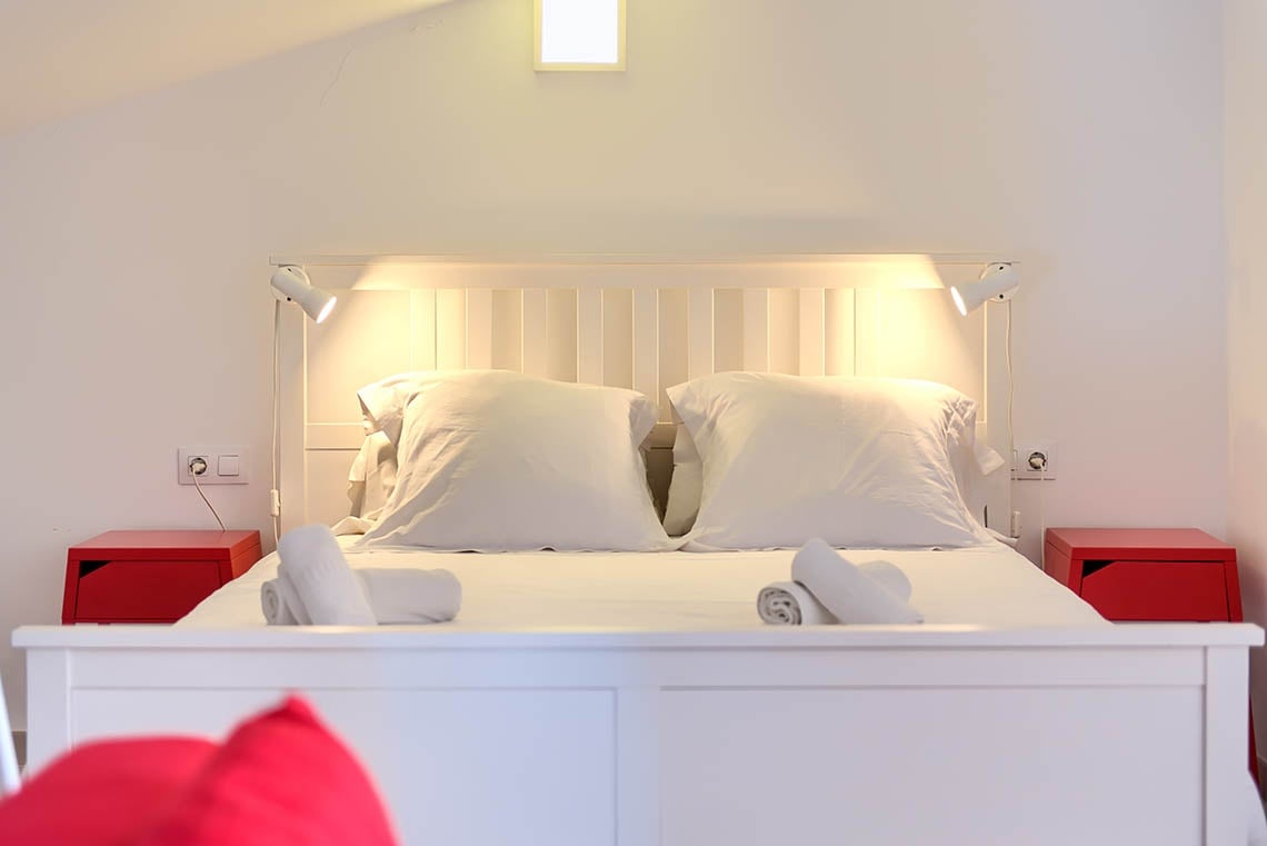 Modernes Hotelzimmer mit Doppelbett und roten Nachttischen bei Sea You: Port Saplaya.