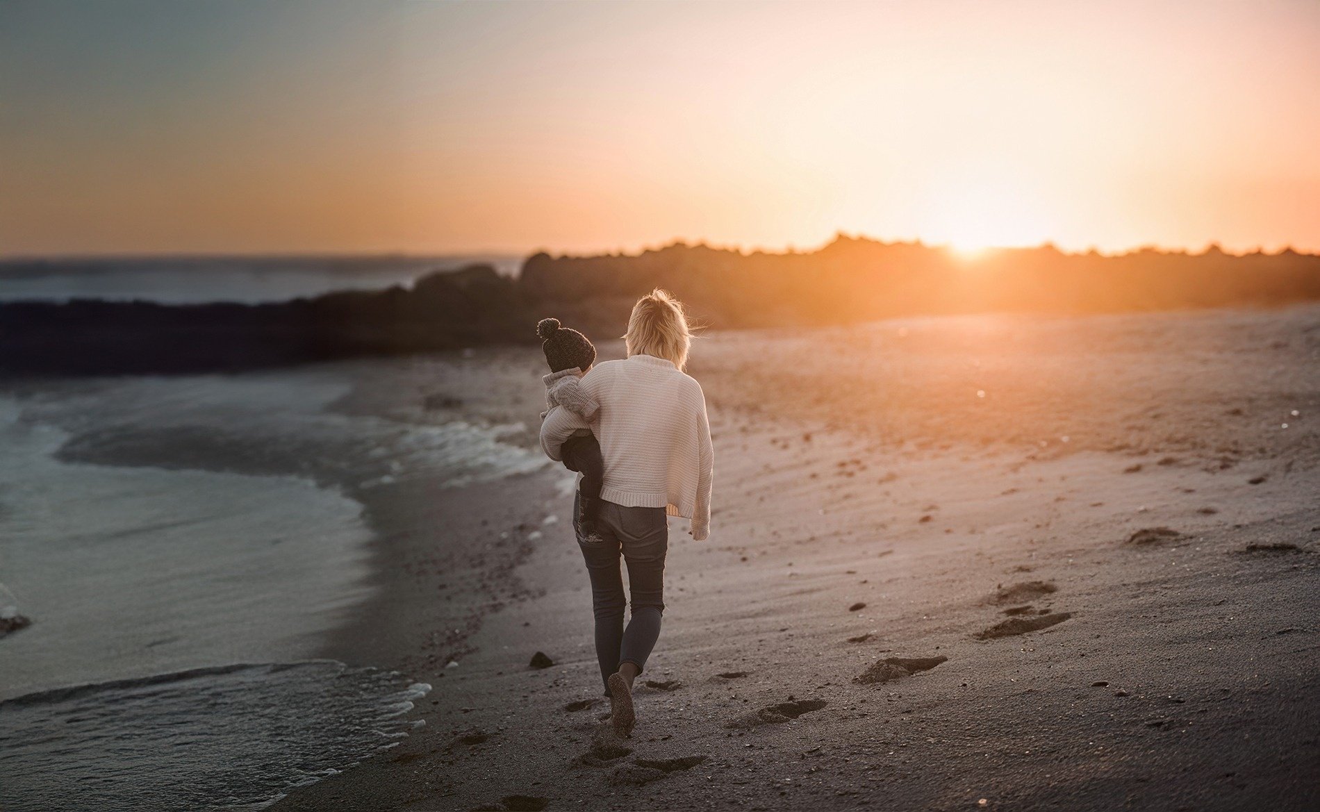 un hombre lleva a una mujer en sus hombros en la playa