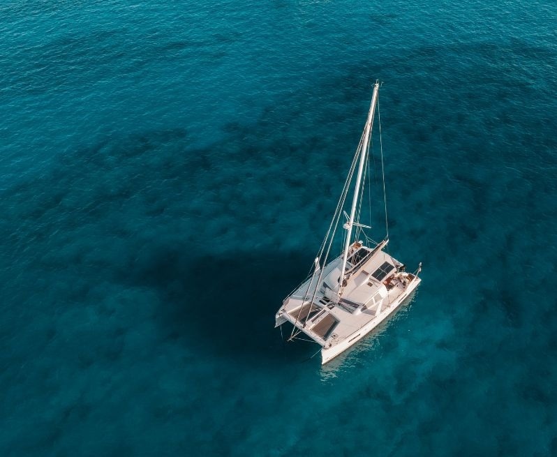 an aerial view of a sailboat in the ocean