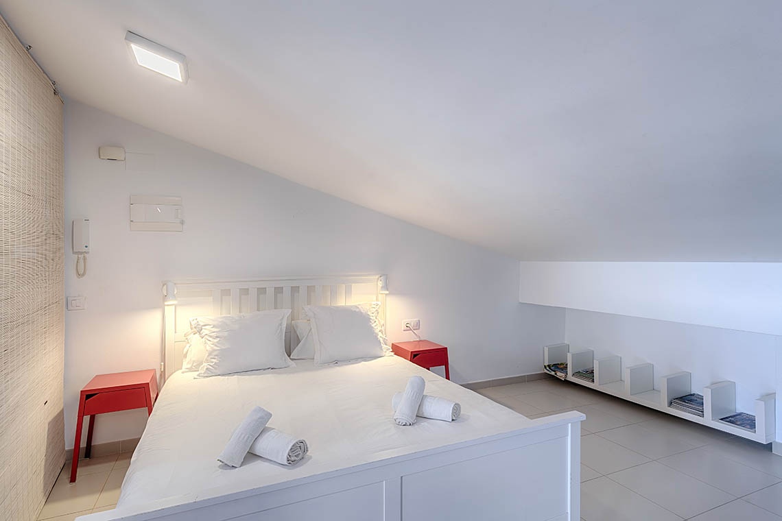 Modernes Schlafzimmer im Sea You: Port Saplaya mit weißem Bett & roten Nachttischen.