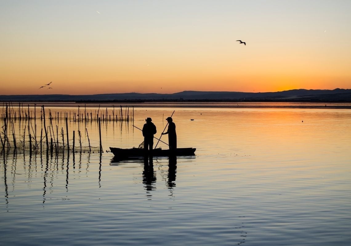 Coucher de soleil sur La Albufera : deux pêcheurs dans un bateau, idéal pour explorer depuis Port Saplaya.