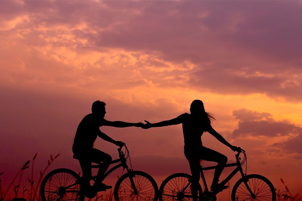 Couple cycling at sunset by the sea. Sea You: Port Saplaya!