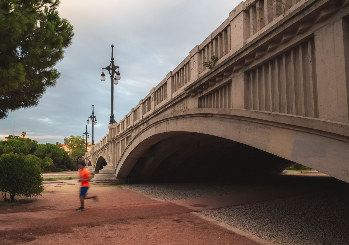 Hombre corriendo bajo un puente histórico en Valencia. ¡El deporte en Valencia te espera en Sea You Hotel!