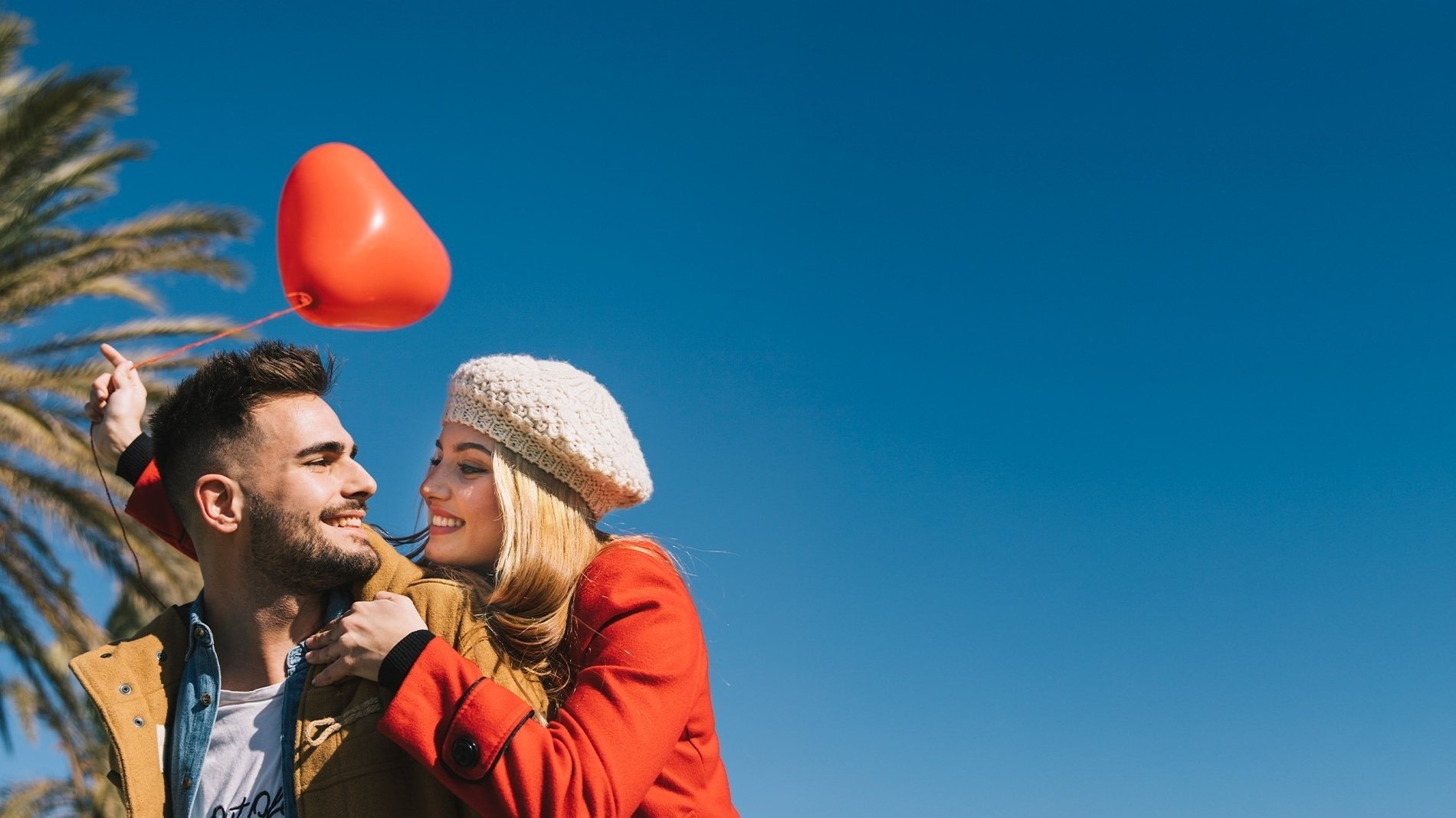 un hombre y una mujer sostienen un globo rojo en forma de corazón