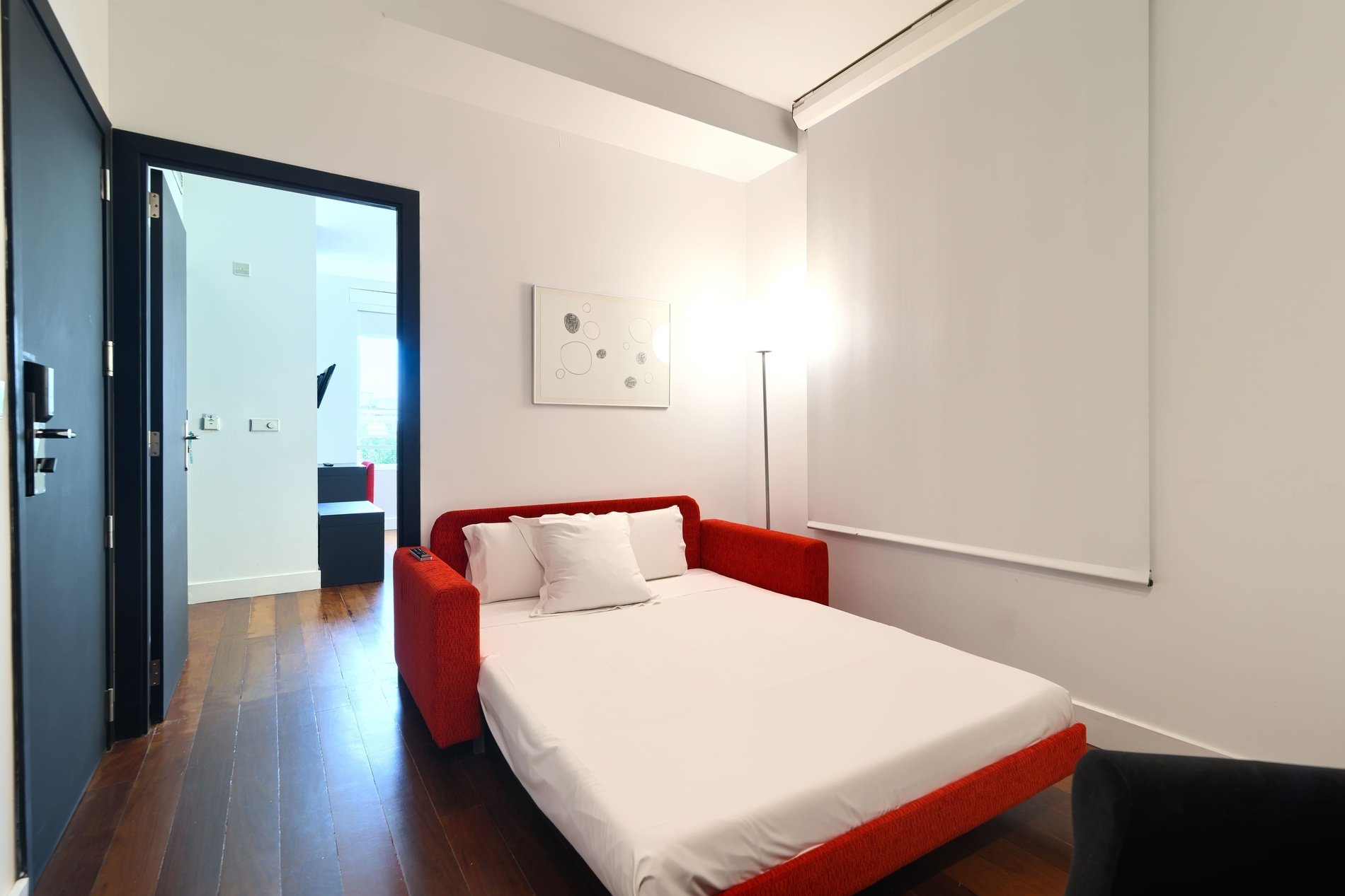 a bedroom with a red couch and a white bed