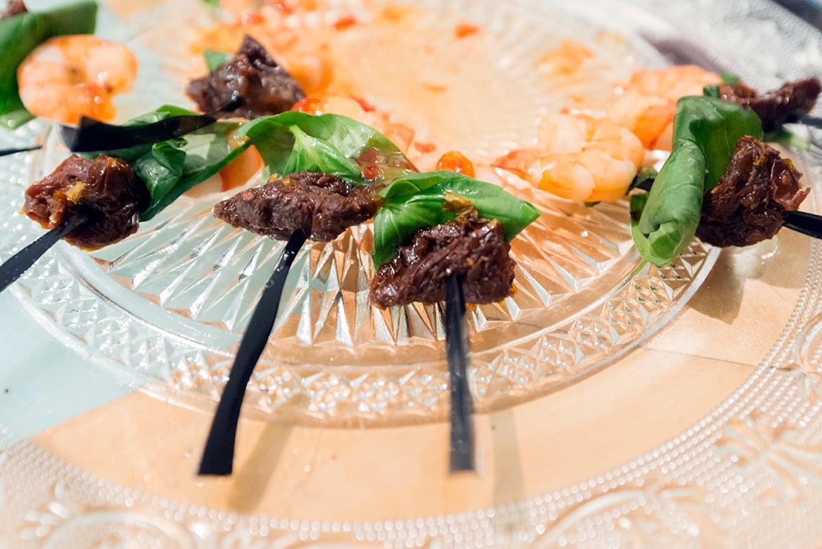 eine Glasplatte mit Garnelen und Fleisch auf Stäbchen