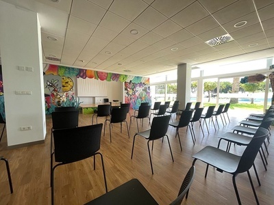 una sala llena de sillas y mesas con un mural en la pared - Eventos locales