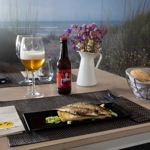 una mesa con un plato de comida y una botella de cerveza