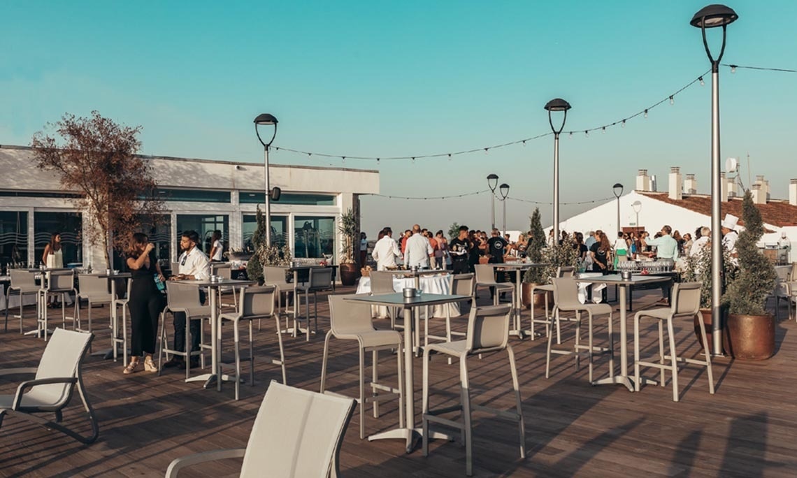un grupo de personas se reúnen en una terraza con mesas y sillas