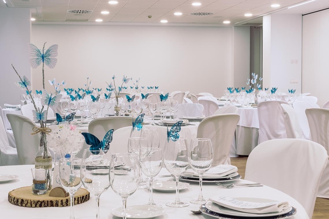 una mesa llena de copas de vino y mariposas azules