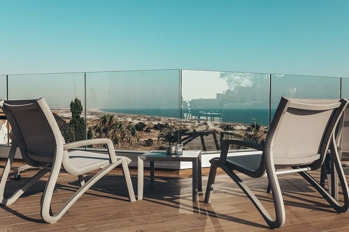 dos sillas y una mesa en un balcón con vista al océano