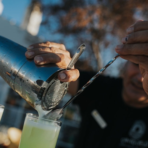 un hombre prepara un cóctel en un shaker de acero inoxidable