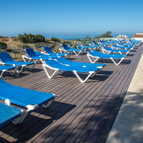 una fila de tumbonas azules están alineadas junto a una piscina