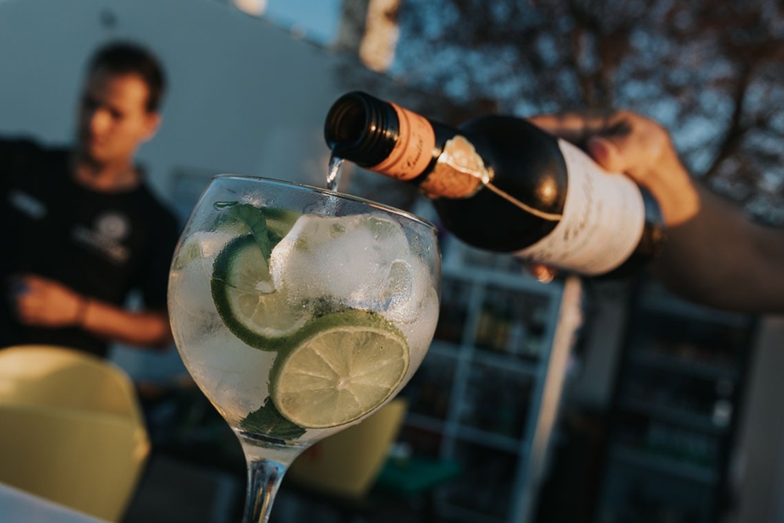 uma garrafa de vinho é derramada em um copo com gelo e limão