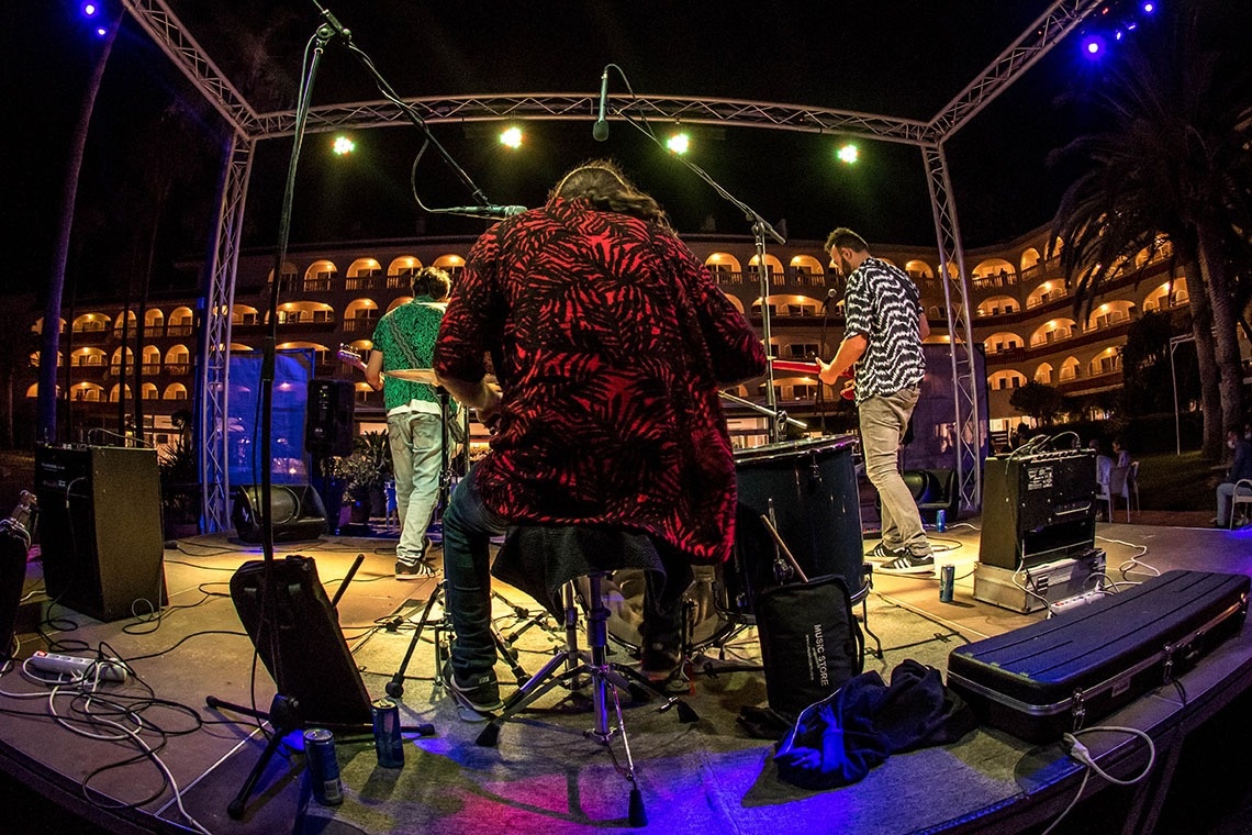 un grupo de músicos se presenta en un escenario con una caja que dice ' fender ' en ella